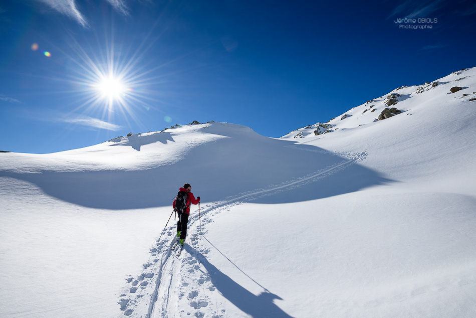 Skieur de randonnee en montee sous le soleil et ciel bleu. Grand-Mont. Massif du Beaufortin.