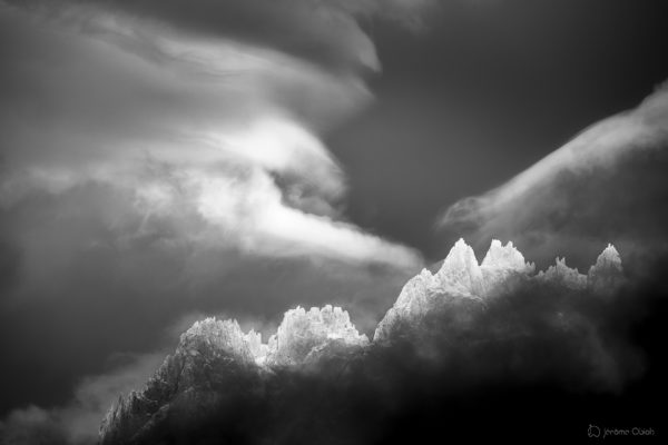 Ciel d'orage en noir et blanc en montagne et lumière éclairant le sommet des aiguilles de Chamonix. Massif du Mont-Blanc.